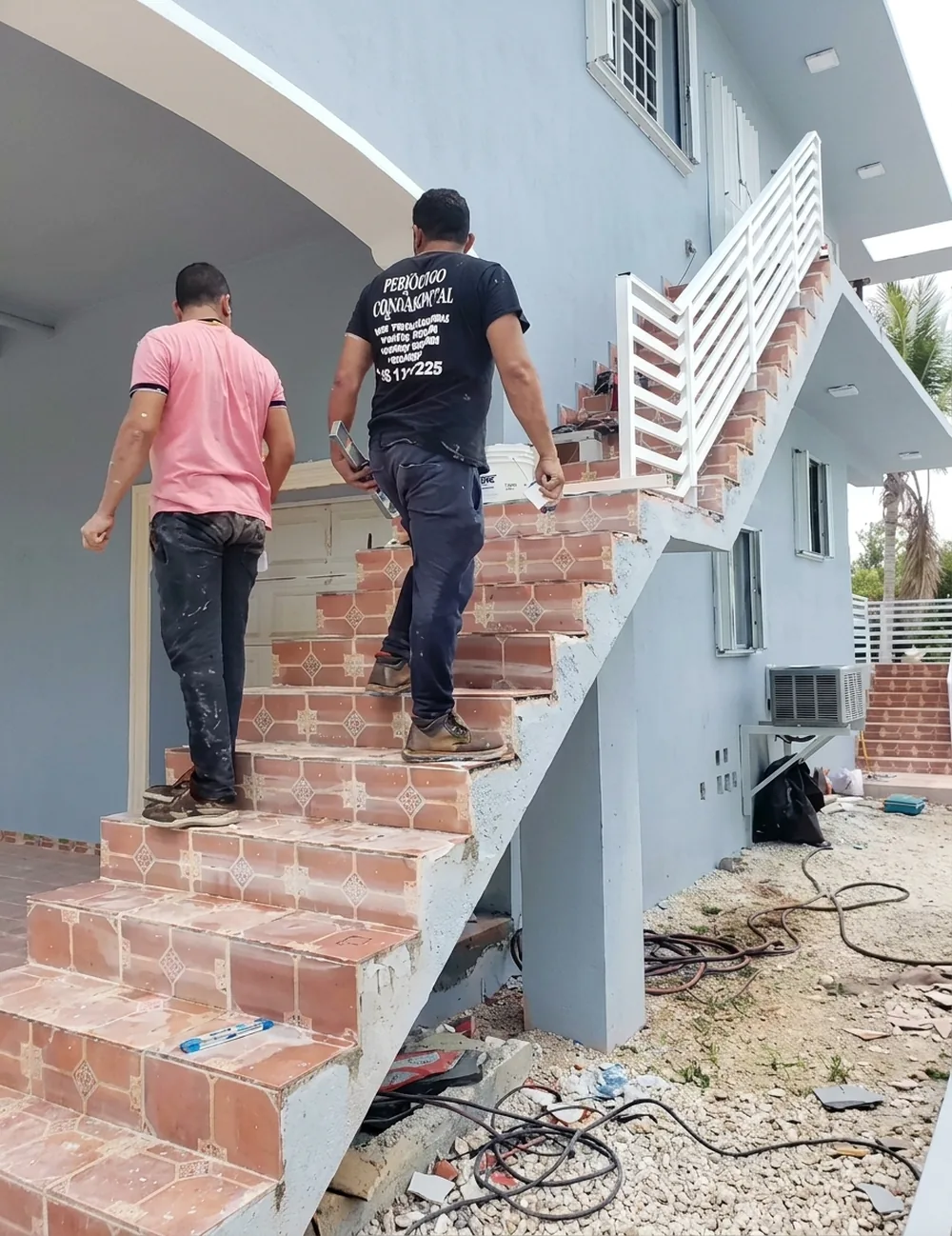 Escalera exterior de ladrillo sin baranda, con el equipo montando la estructura