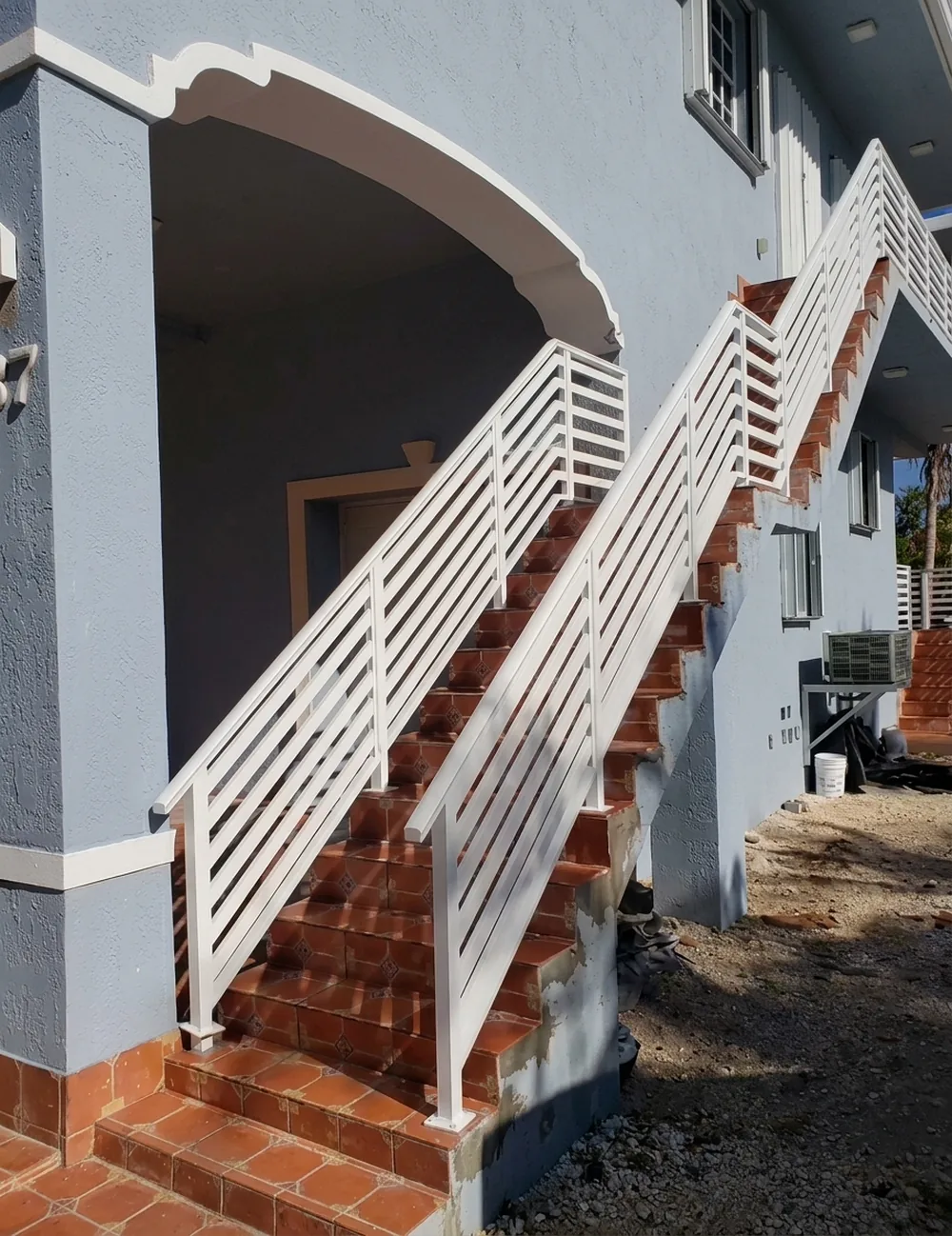 La misma escalera terminada con baranda blanca de aluminio y pasamanos continuo