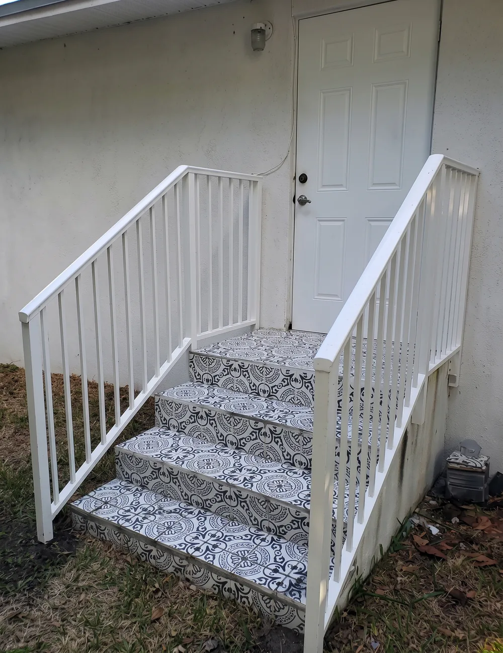 Baranda blanca con pasamanos continuo sobre escalones decorados