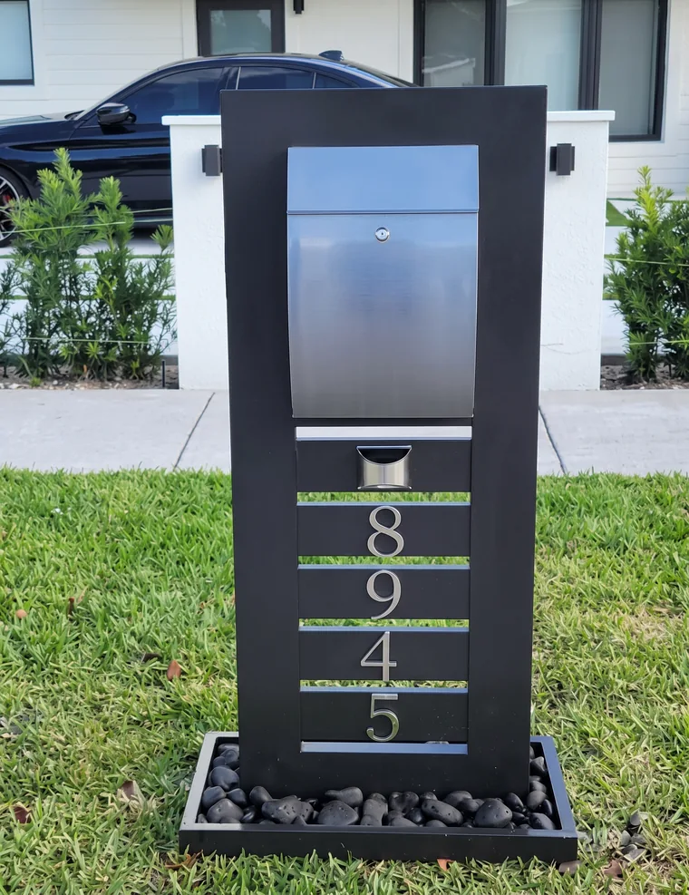 Pedestal negro con buzón de acero inoxidable y número 8945 iluminado