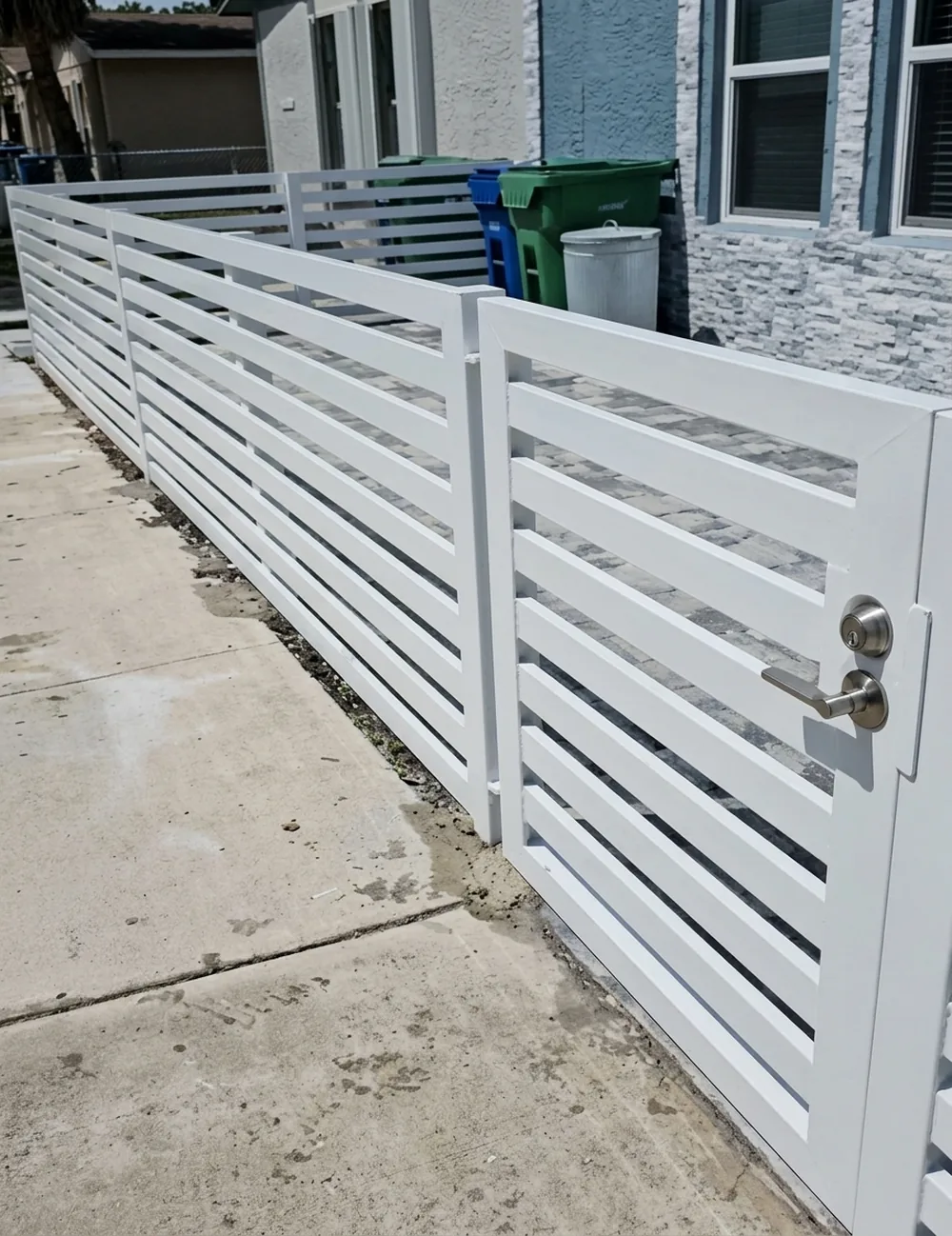 Cerca blanca de lama horizontal con puerta de acceso al costado de la casa