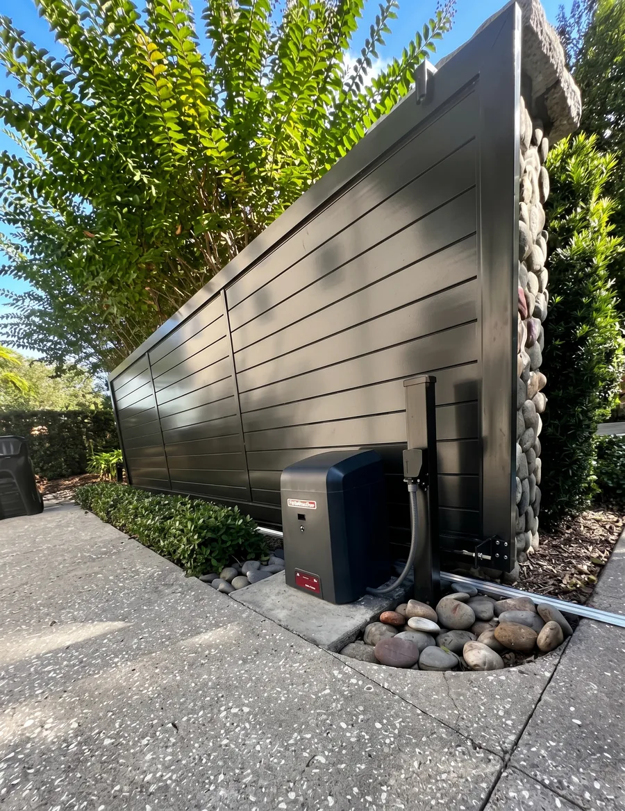 Portón corredizo de aluminio gris con operador automático instalado a un costado