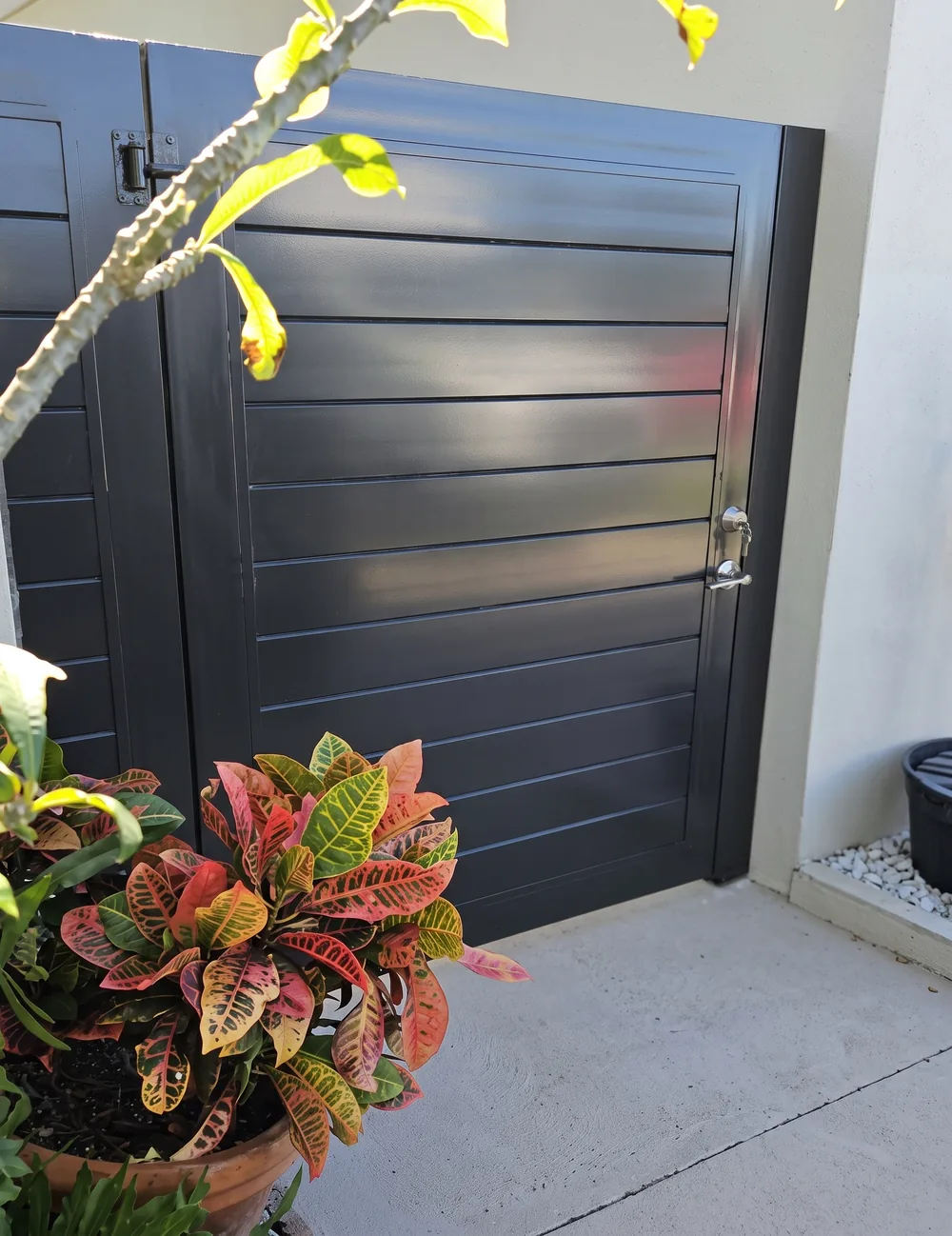 Puerta de lama horizontal gris oscuro instalada en el costado de una vivienda