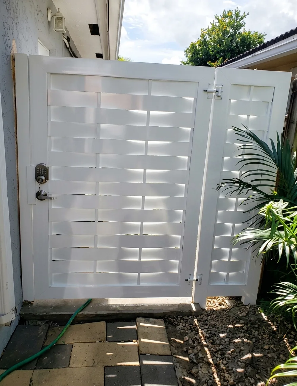 Puerta blanca de diseño calado geométrico en el acceso lateral de una casa